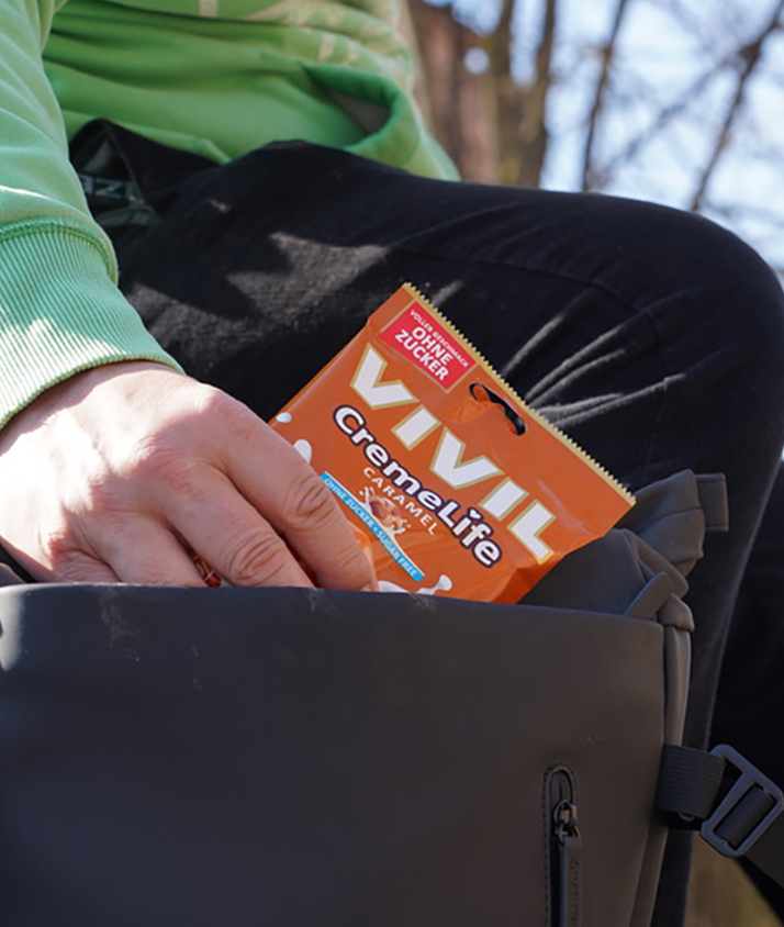 Bonbontüte Caramel wird aus dunklem Rucksack gezogen Bonbontüte Caramel wird aus dunklem Rucksack gezogen