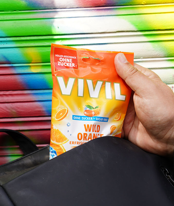 Orangenbonbon wird aus Rucksack gezogen Orangenbonbon mit Rucksack