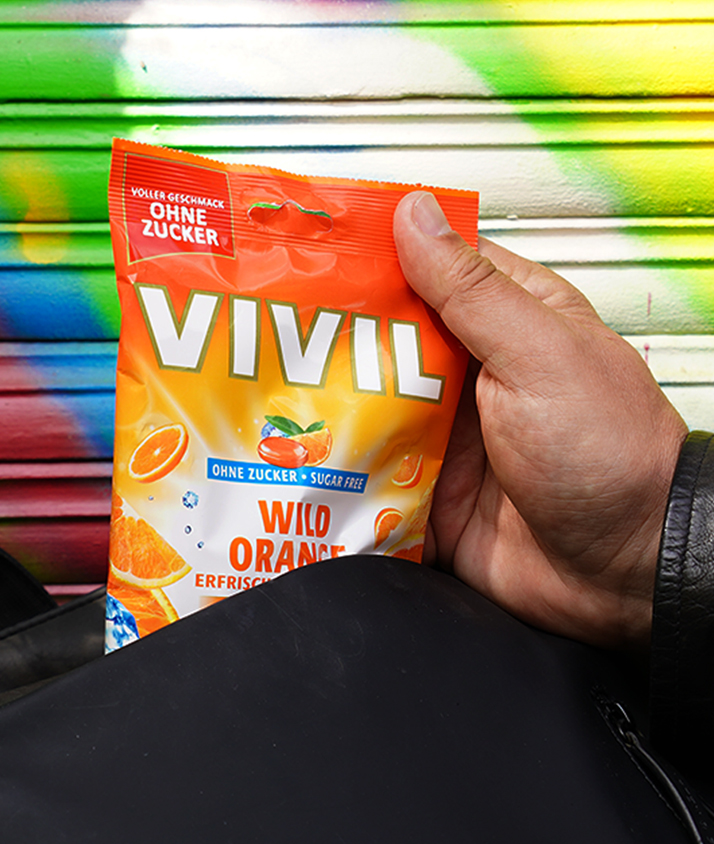 Orangenbonbons werden aus einem schwarzen Rucksack gezogen Orangenbonbons werden aus einem schwarzen Rucksack gezogen